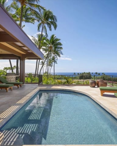 Infinity pool at sunset with ocean views and tropical gardens